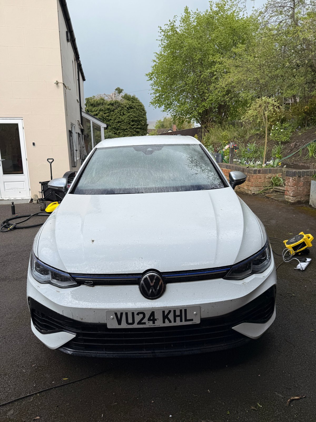White Volkswagen electric car with VU24 KHL license plate parked in a driveway next to a house