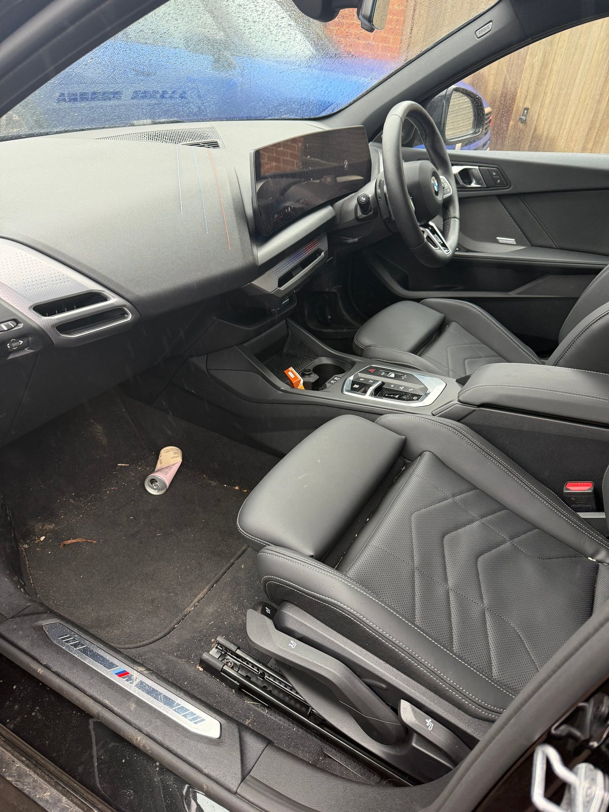 Modern car interior with gray leather seats, digital dashboard, steering wheel, and center console viewed from driver side door